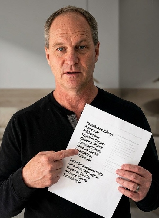 A still from Sleep Essentials&rsquo; own video: a presenter to camera, holding a printed list of fire-retardant chemicals used in conventional mattresses.